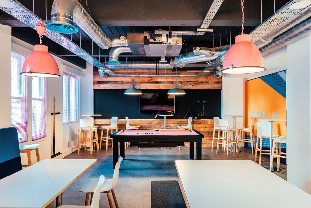 Modern office breakout room with a pool table and blackboard.