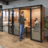 Era Hoozone Jimmy Working Pod office acoustics for meetings in grey with dotted front manifestations four person enclosed pod with fabric back in orange and grey fabric with LED lighting