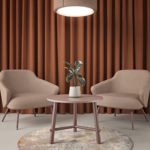 Serenity circular coffee table in natural oak with a plant on top next to 2 chairs.