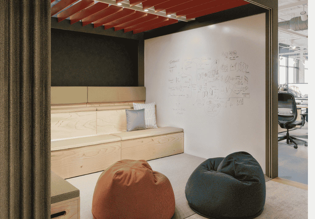 Office with acoustic phone booths placed both centrally with glazing and along walls, combined with tiered seating