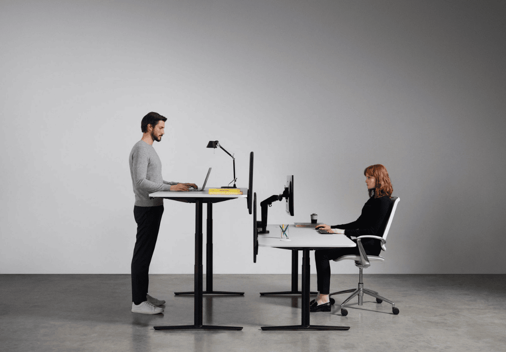 Modern office with height-adjustable standing desks and employees alternating between sitting and standing