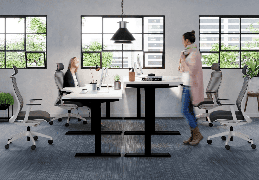 Modern office with height-adjustable standing desks and employees alternating between sitting and standing
